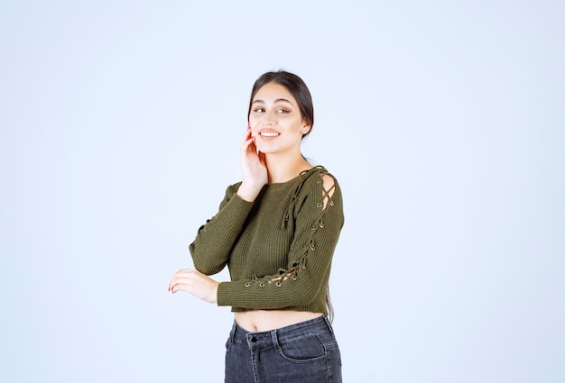 Vrij jonge vrouw die gelukkig op witte muur voelt