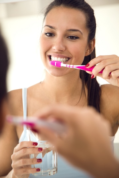 Vrij jonge vrouw die haar tanden in de badkamers borstelt.