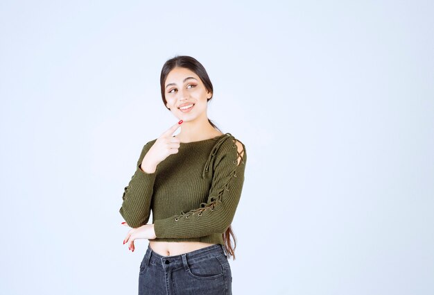 Vrij jonge vrouw die op haar zij op witte muur richt