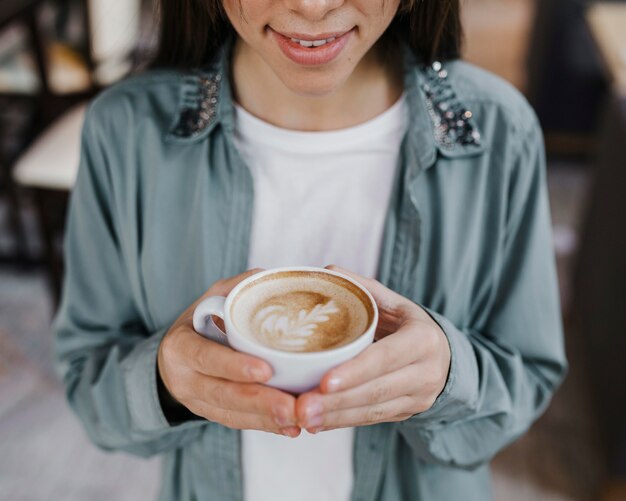 Vrij jonge vrouw die van een koffiekop geniet