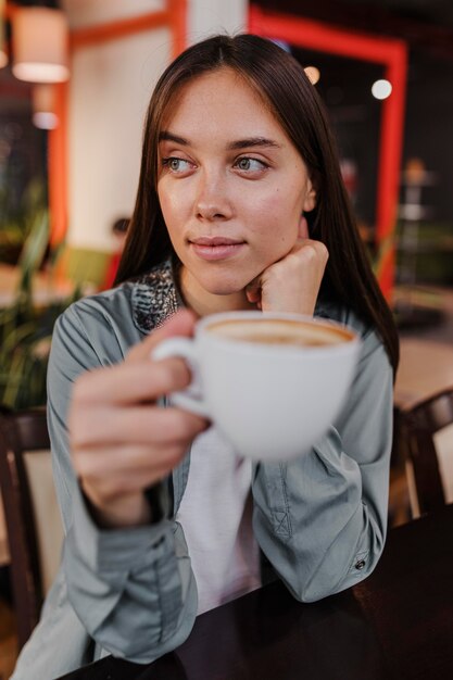 Vrij jonge vrouw die van een koffiekop geniet