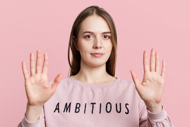 Gratis foto vrij jonge vrouw met lang donker staight haar vertoont stopbord