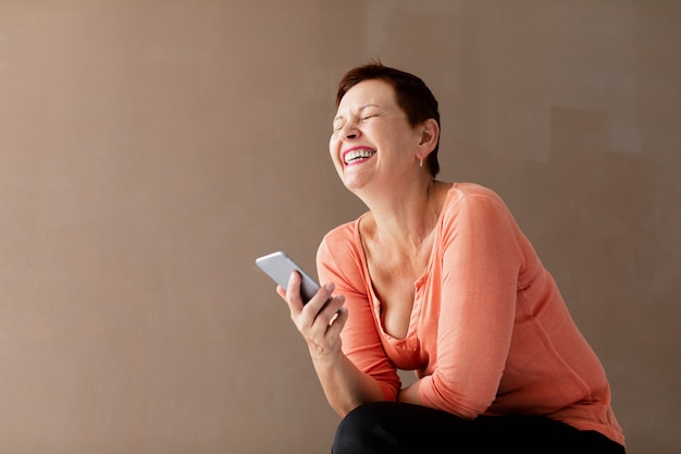 Vrij rijpe vrouw met telefoon het lachen