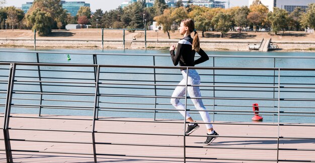 Vrij sportieve jonge vrouwenjogging bij park