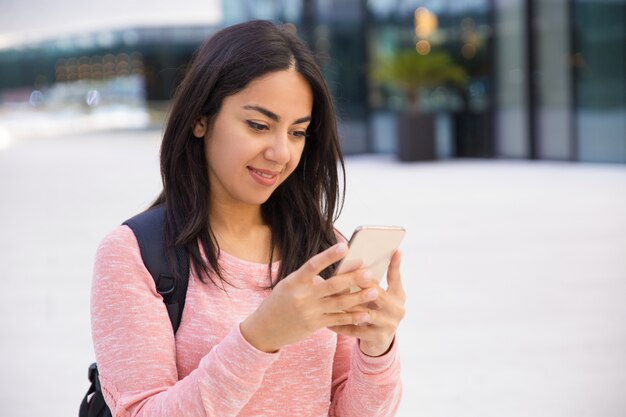 Vrij studentmeisje die van de inhoud smartphone gebruiken