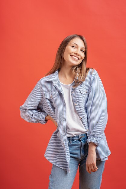 Vrij vrouwelijk model poseren met een lachend gezicht expressie op rode muur