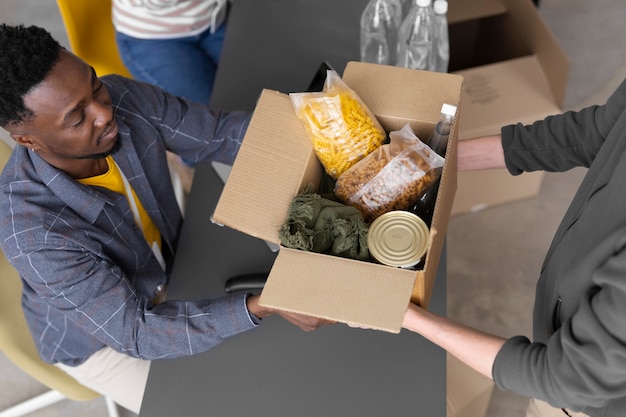 Vrijwilliger die een donatiebox ophaalt van een andere vrijwilliger