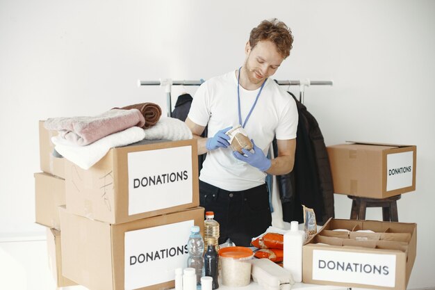Vrijwilliger verzamelt dingen uit donaties. Guy pakt dozen met dingen. De mens vergelijkt begiftiging.
