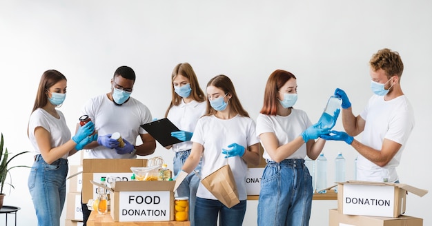 Vrijwilligers met handschoenen en medische maskers doos voorbereiden op donatie