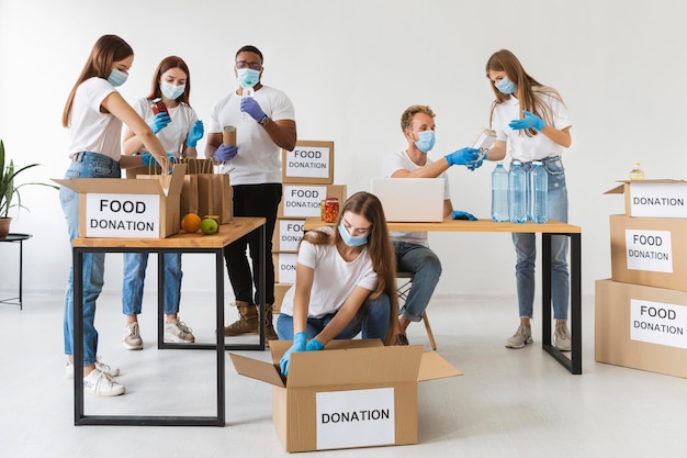 Vrijwilligers met medische maskers en handschoenen die donatiedozen voorbereiden