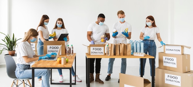 Vrijwilligers met medische maskers en handschoenen die dozen voorbereiden voor donatie