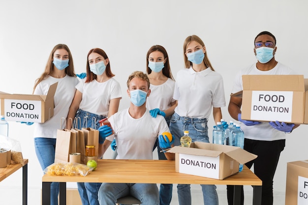 Vrijwilligers met medische maskers poseren samen met donatieboxen