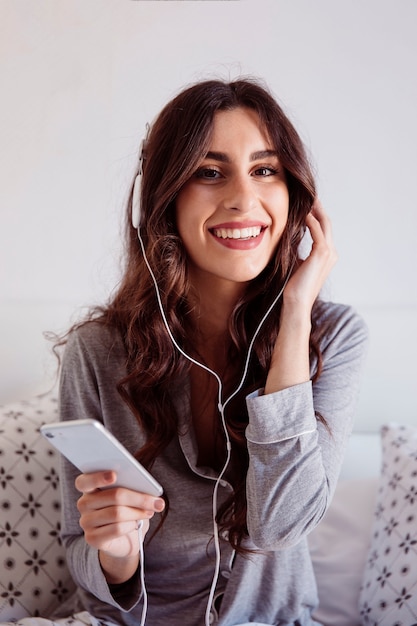 Gratis foto vrolijk brunette die aan muziek luisteren