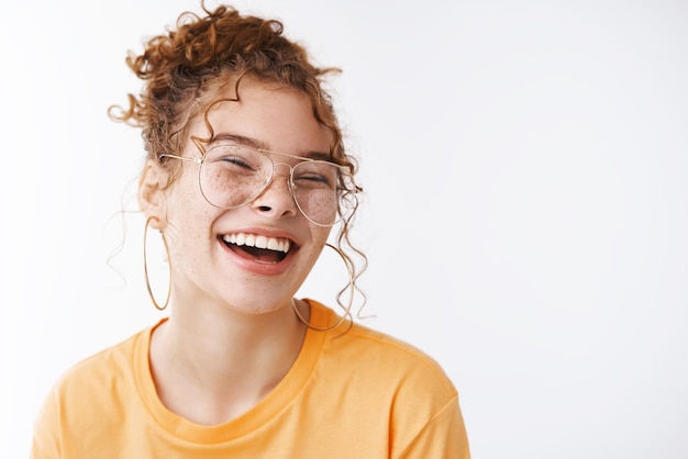 vrolijk gelukkig jong gelukkig roodharig meisje met een bril rommelig krullend broodje lachen