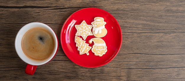 Vrolijk kerstfeest met zelfgemaakte koekjes en koffiekopje op houten tafel achtergrond. kerstavond, feest, vakantie en gelukkig nieuwjaarsconcept