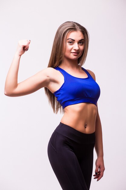 Vrolijk lachende gemengde race sportieve vrouw biceps demonstreren, geïsoleerd op een witte achtergrond