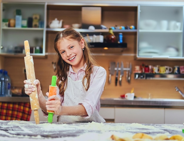 Gratis foto vrolijk meisje dat deeg kookt in de keuken.