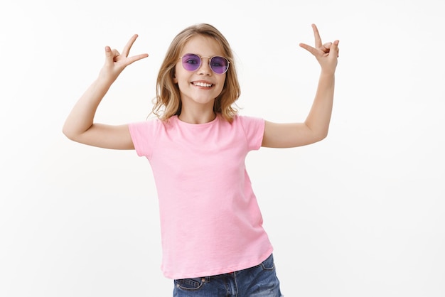 Vrolijk, stijlvol en glamoureus jong meisje geniet van zomervakanties zonder school, draag een zonnebril roze t-shirt