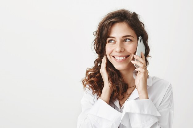 Vrolijke aantrekkelijke vrouw praten aan de telefoon en glimlachen