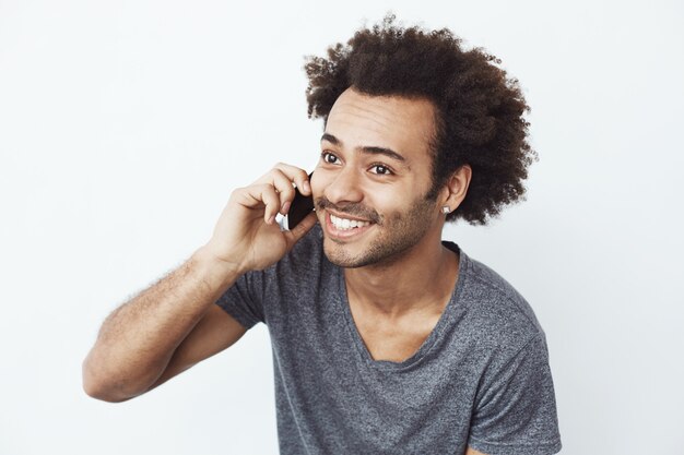 Vrolijke Afrikaanse man die lacht spreken op telefoon.