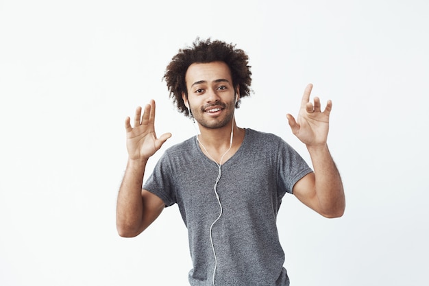 Vrolijke Afrikaanse man luisteren naar muziek in hoofdtelefoons dansen zingen.