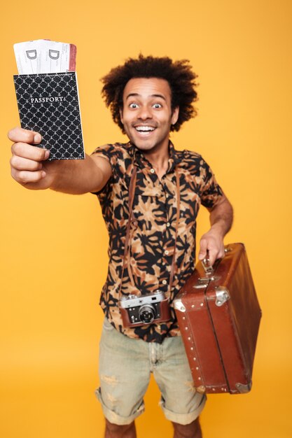 Vrolijke Afrikaanse man met paspoort en koffer