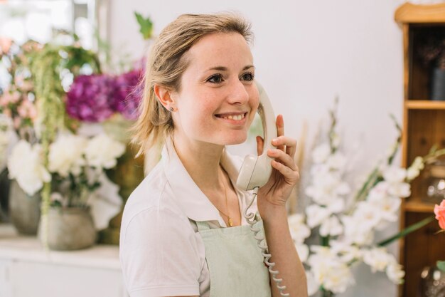 Vrolijke bloemist die op telefoon spreekt