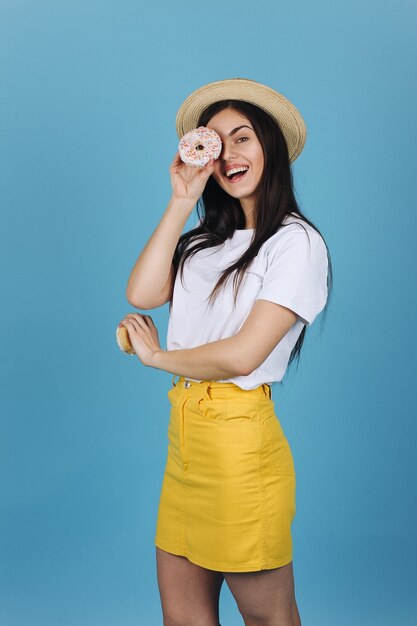 Vrolijke brunette heeft plezier poseren met heerlijke donuts in de studio