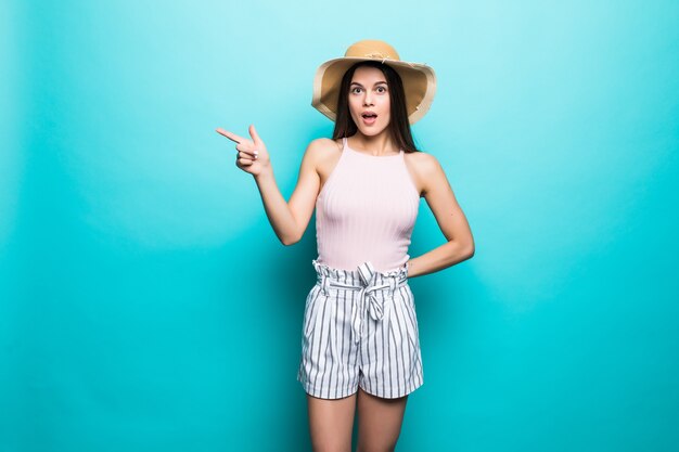 Vrolijke brunette in wit t-shirt en bril aan de muur. van blauw toont een vinger opzij