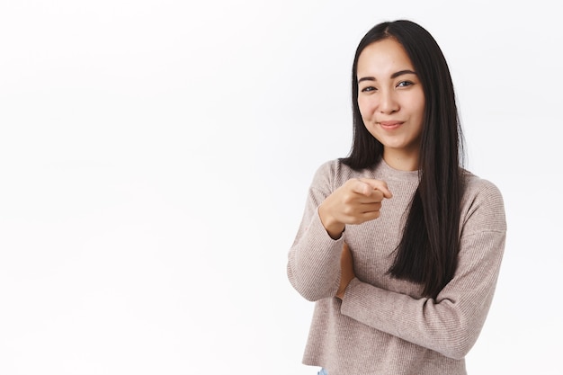 Vrolijke brutale en zelfverzekerde aziatische vrouw die keuze maakt, je kiest, camera richt en tevreden glimlacht, nodigt uit voor een interview om haar bedrijf te werken