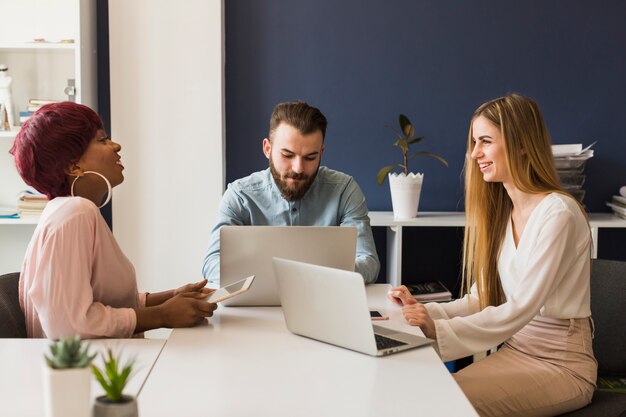 Vrolijke collega&#39;s met behulp van laptops