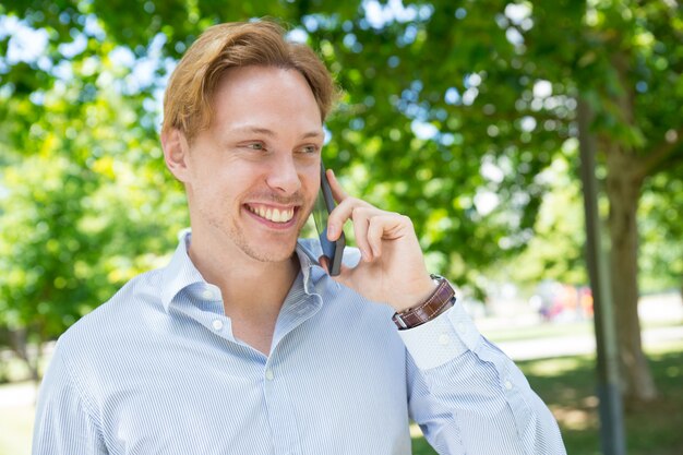 Vrolijke gelukkige ondernemer die van aardig telefoongesprek geniet