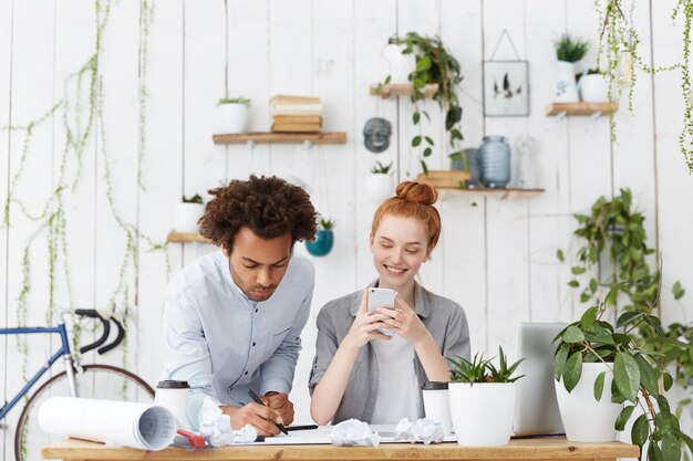 Vrolijke glimlachende jonge roodharige blanke vrouw ingenieur genieten van online communicatie