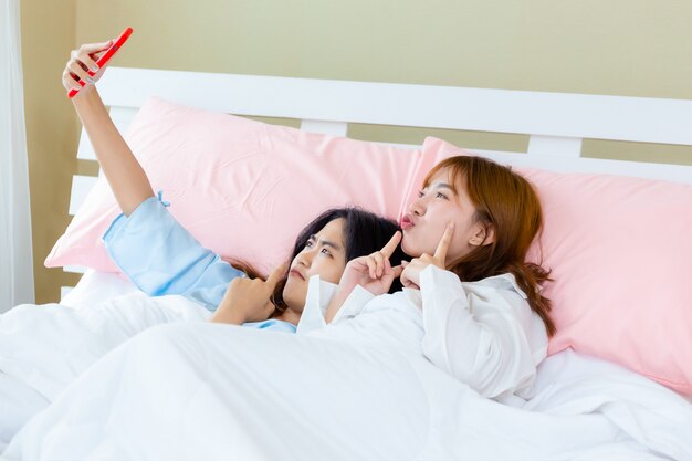 Vrolijke het gebruikssmartphone van de tienervrouw selfie op bed