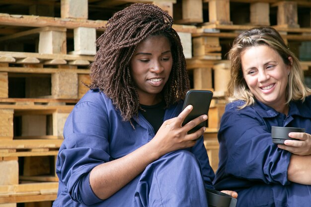 Vrolijke industriële arbeiders die cel gebruiken tijdens koffiepauze