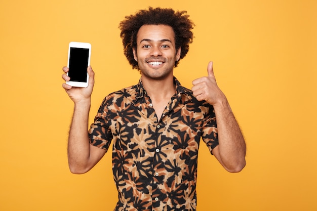 Vrolijke jonge Afro-Amerikaanse man met leeg scherm mobiele telefoon