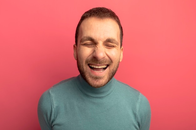 Gratis foto vrolijke jonge blanke man lachen met gesloten ogen geïsoleerd op karmozijnrode achtergrond
