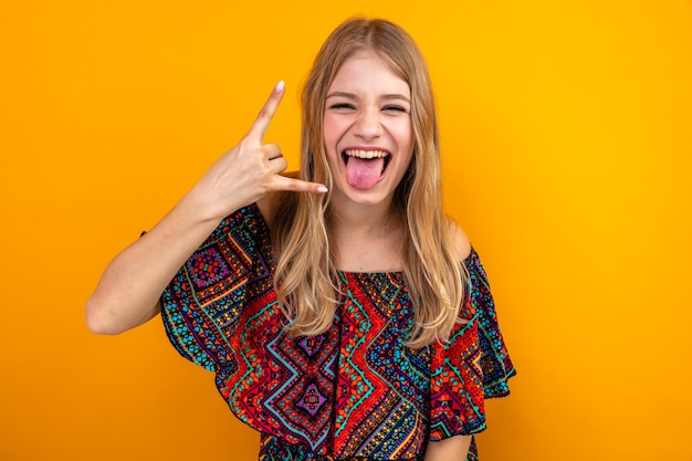 Vrolijke jonge blonde Slavische meid die haar tong steekt en hoorns gebaart