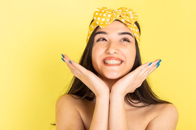 Vrolijke jonge dame houdt haar handen omhoog en lacht op gele achtergrond foto van hoge kwaliteit