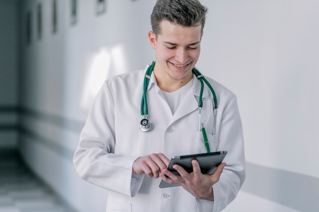 Gratis foto vrolijke jonge dokter met behulp van tablet pc