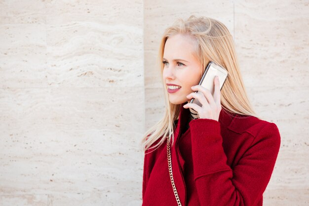 Vrolijke jonge Kaukasische vrouw lopen buiten praten via de telefoon