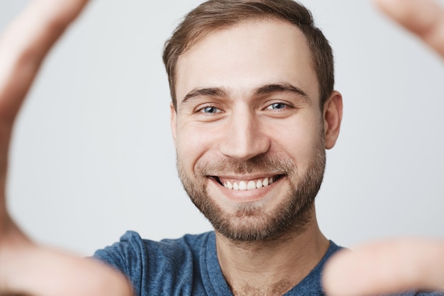 Gratis foto vrolijke jonge man met baard, glimlachend nemen selfie