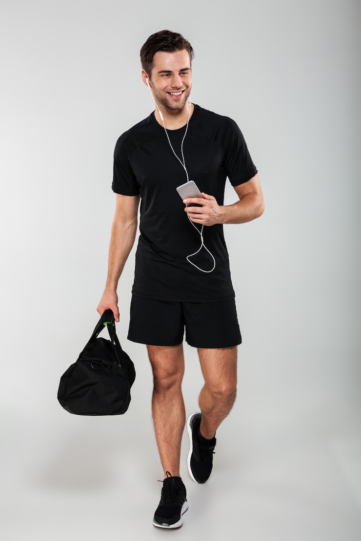 Gratis Foto vrolijke jonge sportenmens die mobiele telefoon het luisteren muziek gebruiken