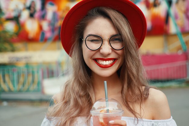 Vrolijke jonge vrouw die een drank houdt terwijl het glimlachen