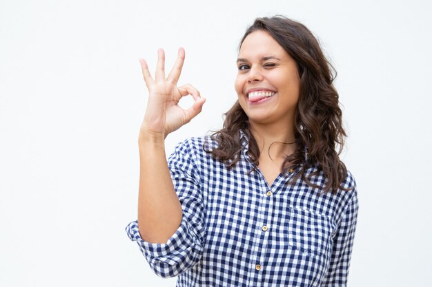 Vrolijke jonge vrouw die ok teken toont