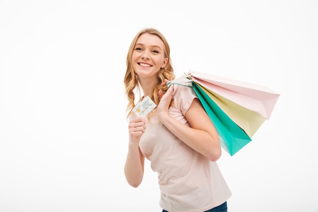 Vrolijke jonge vrouw met creditcard en boodschappentassen.