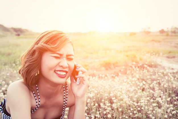 Vrolijke jonge vrouw te praten aan de telefoon bij zonsondergang