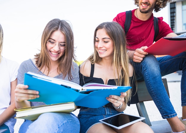 Gratis foto vrolijke jonge vrouwen die handboek samen lezen