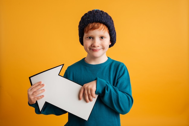 Vrolijke kleine roodharige jongen bedrijf pijl.