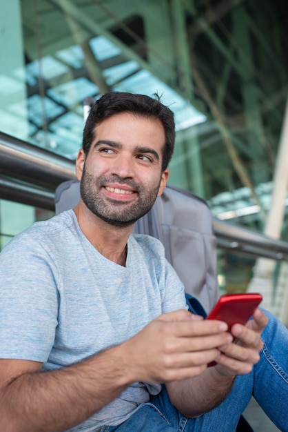 Vrolijke knappe smartphone van de mensenholding bij luchthaven